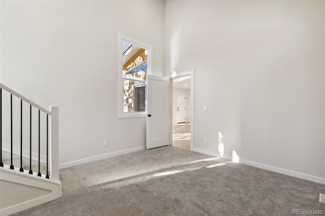 carpeted empty room featuring a towering ceiling