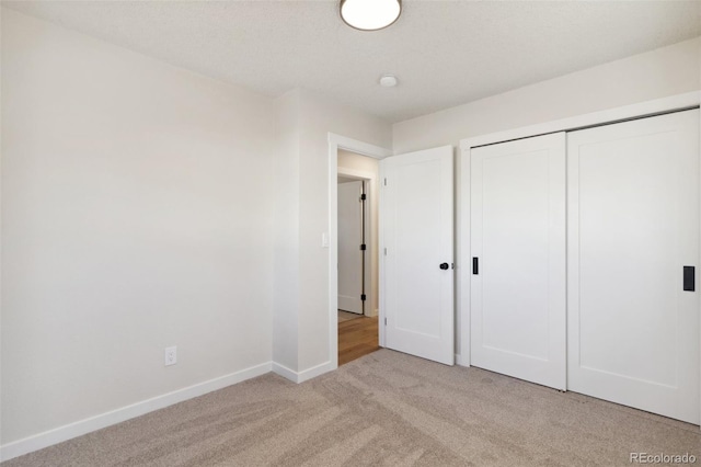 unfurnished bedroom featuring light carpet and a closet