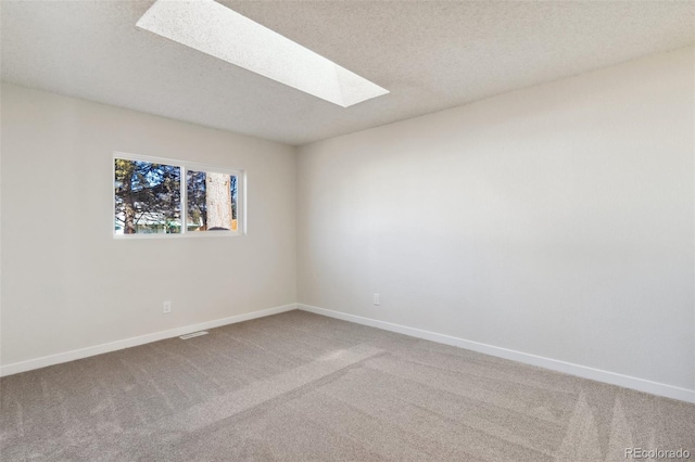 empty room featuring carpet, a textured ceiling, and a skylight