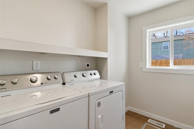 washroom featuring washing machine and dryer and light hardwood / wood-style flooring