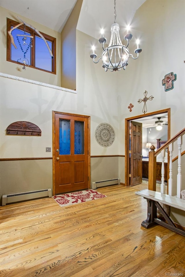 entryway with an inviting chandelier, a baseboard radiator, hardwood / wood-style floors, and a towering ceiling