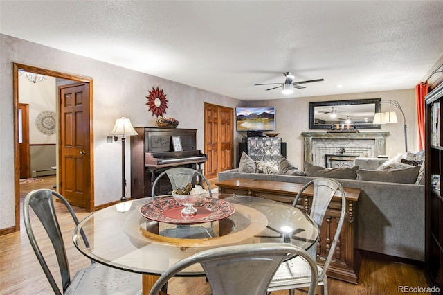 dining area featuring hardwood / wood-style flooring, a baseboard radiator, ceiling fan, and a textured ceiling