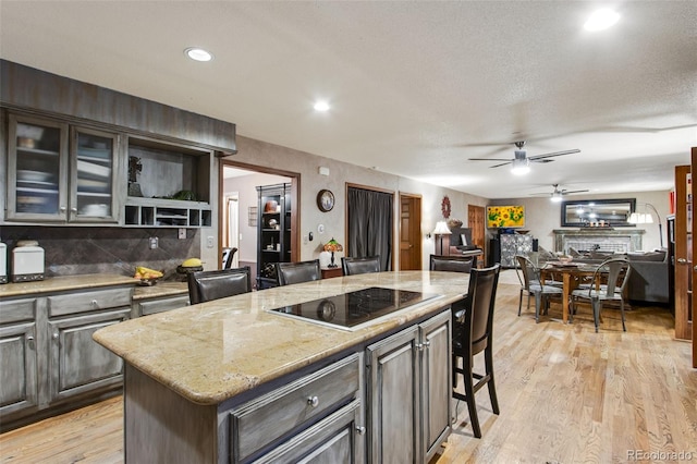 kitchen with black electric cooktop, dark brown cabinetry, a kitchen breakfast bar, and a center island