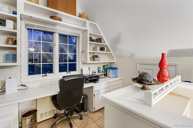 home office featuring lofted ceiling, built in desk, and light tile patterned floors