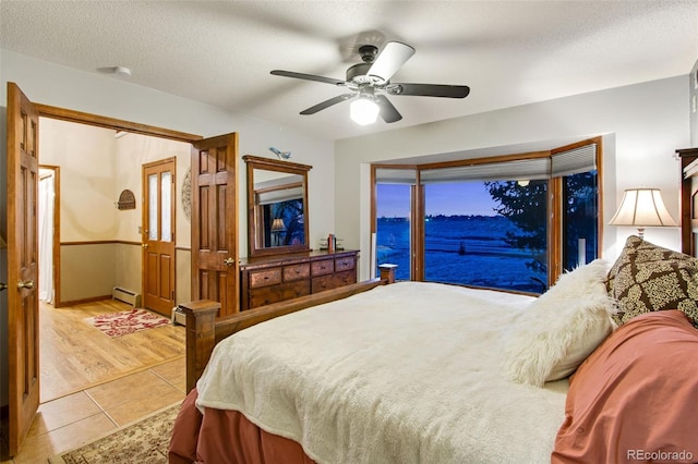 bedroom featuring a baseboard heating unit, light tile patterned floors, a textured ceiling, and ceiling fan