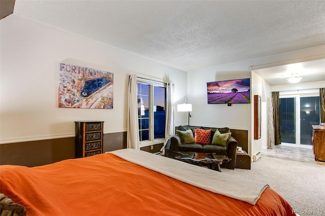 carpeted bedroom featuring baseboard heating and a textured ceiling