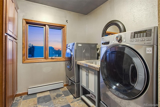 laundry area with a baseboard heating unit, cabinets, and washer and dryer