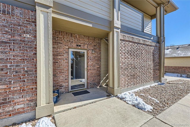 view of exterior entry featuring brick siding