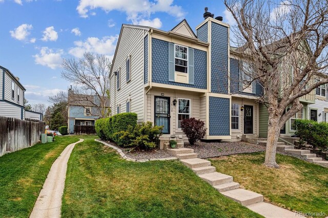 townhome / multi-family property with fence, a chimney, and a front yard