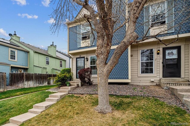 exterior space featuring entry steps, fence, and a front lawn
