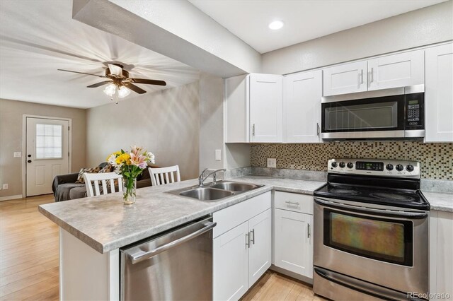 kitchen featuring a sink, appliances with stainless steel finishes, backsplash, and a peninsula