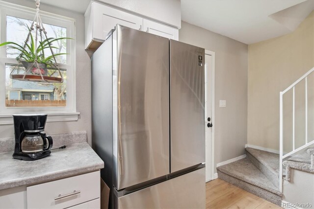 kitchen with light wood-style floors, freestanding refrigerator, white cabinetry, and light countertops