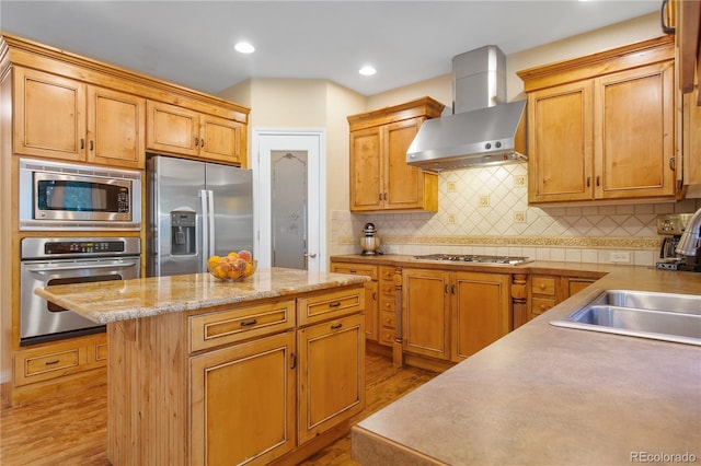 kitchen featuring decorative backsplash, wall chimney exhaust hood, hardwood / wood-style flooring, a center island, and stainless steel appliances