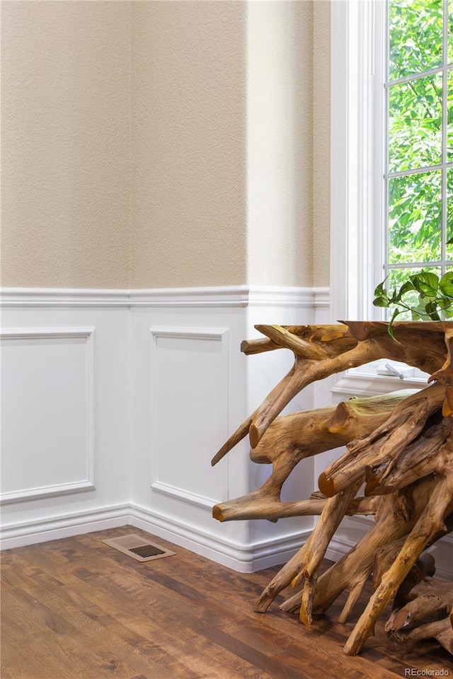 room details with visible vents, wood finished floors, and a wainscoted wall