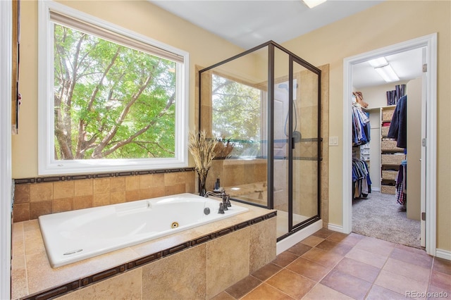 full bath with a walk in closet, a garden tub, a stall shower, and tile patterned flooring