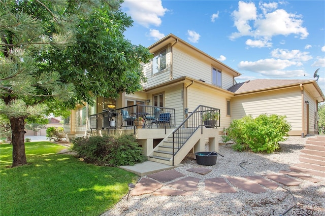 back of property featuring stairway, a lawn, and a wooden deck