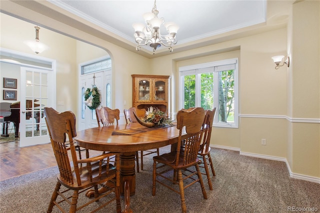 dining area with an inviting chandelier, crown molding, a tray ceiling, and wood-type flooring