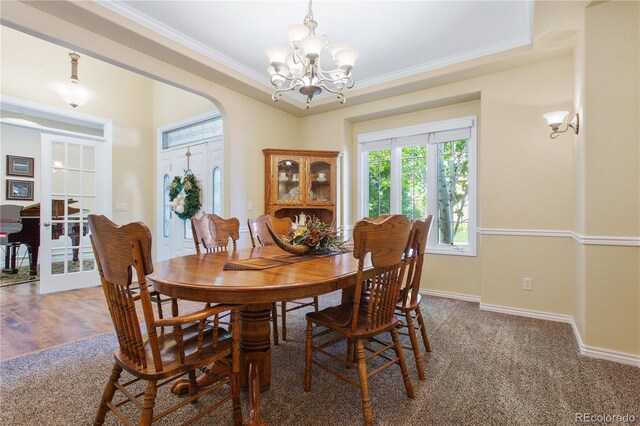 dining area with a tray ceiling, arched walkways, crown molding, baseboards, and a chandelier