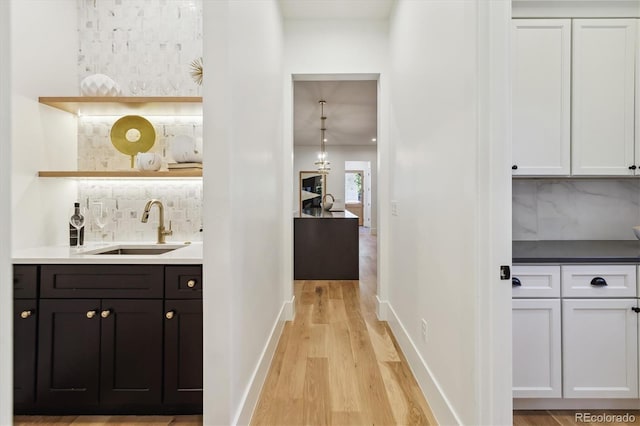 bar with sink, white cabinets, and tasteful backsplash