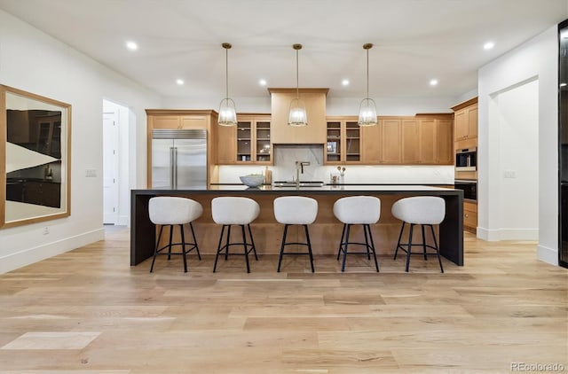 kitchen featuring backsplash, hanging light fixtures, appliances with stainless steel finishes, and a center island with sink