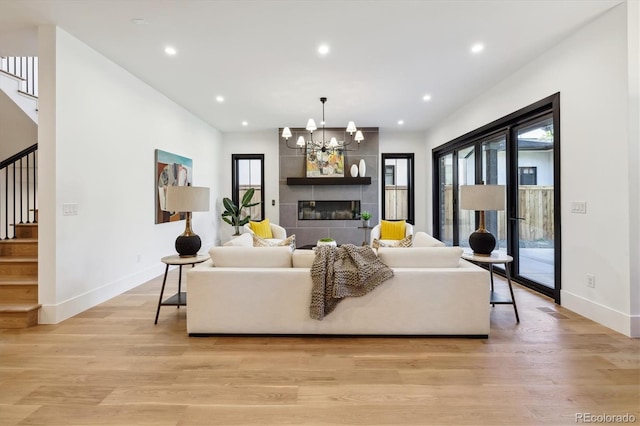 living room featuring light hardwood / wood-style flooring, an inviting chandelier, and a tiled fireplace