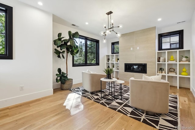 living room featuring light wood-type flooring, a chandelier, and a fireplace