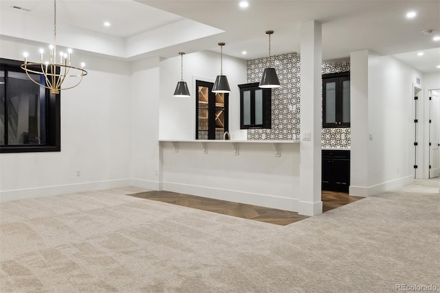 kitchen with a notable chandelier, kitchen peninsula, pendant lighting, a breakfast bar, and backsplash