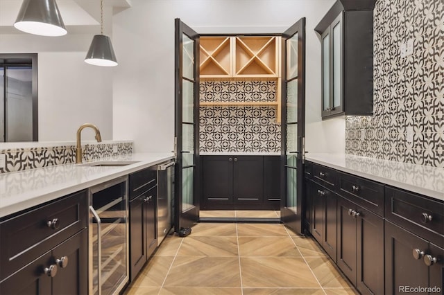 kitchen with decorative backsplash, sink, hanging light fixtures, and wine cooler