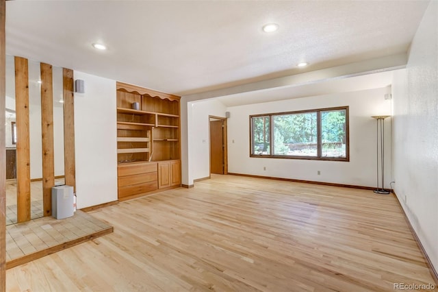 unfurnished living room featuring light hardwood / wood-style floors and built in shelves