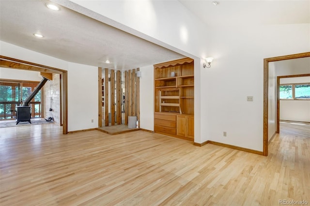 interior space with built in features, a wood stove, and light wood-type flooring