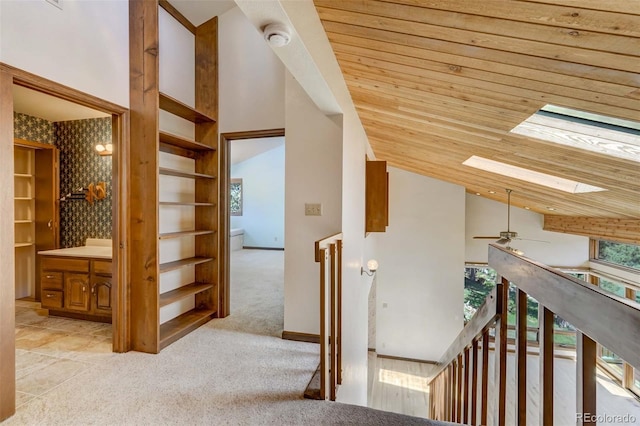 corridor with a skylight, carpet floors, wooden ceiling, and high vaulted ceiling