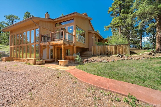 back of house with a wooden deck and a lawn