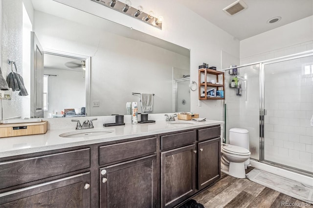 bathroom with double vanity, wood finished floors, a sink, and visible vents