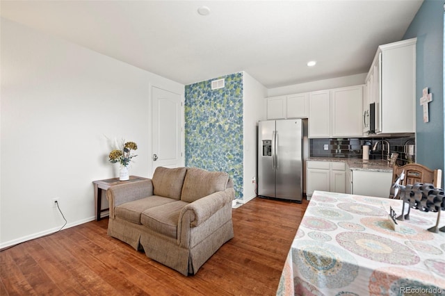 interior space featuring backsplash, hardwood / wood-style floors, appliances with stainless steel finishes, and white cabinets