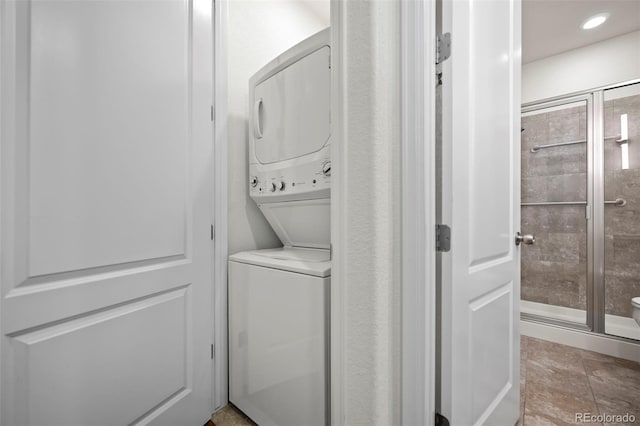 laundry room featuring stacked washer and clothes dryer and light tile patterned floors