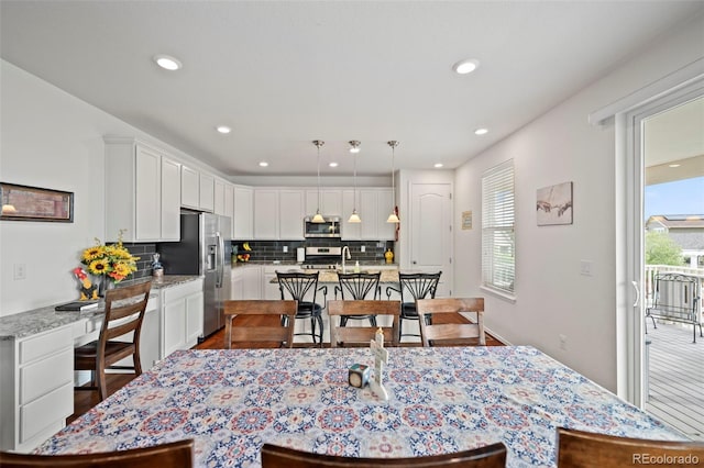 kitchen with backsplash, plenty of natural light, stainless steel appliances, and pendant lighting