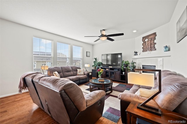 living room featuring ceiling fan, hardwood / wood-style floors, and a tile fireplace