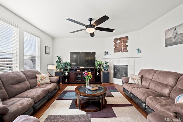 living room with wood-type flooring, ceiling fan, and a tile fireplace