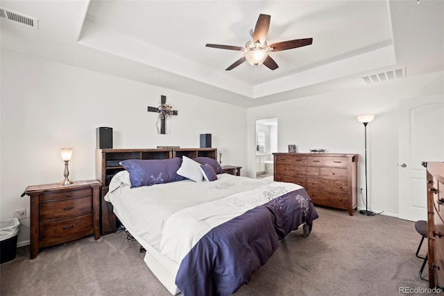 bedroom featuring ceiling fan, a raised ceiling, and light carpet