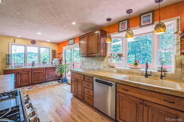 570 Columbine Ave, Golden, CO 80401 - kitchen with stainless steel dishwasher, brown cabinetry, light wood-type flooring, hanging light fixtures, and recessed lighting