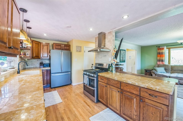 570 Columbine Ave, Golden, CO 80401 - kitchen with appliances with stainless steel finishes, wall chimney exhaust hood, light countertops, brown cabinetry, and a peninsula