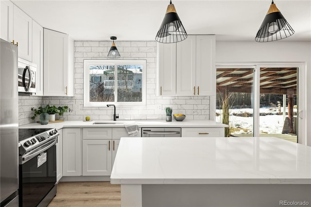 kitchen with sink, white cabinetry, appliances with stainless steel finishes, and hanging light fixtures