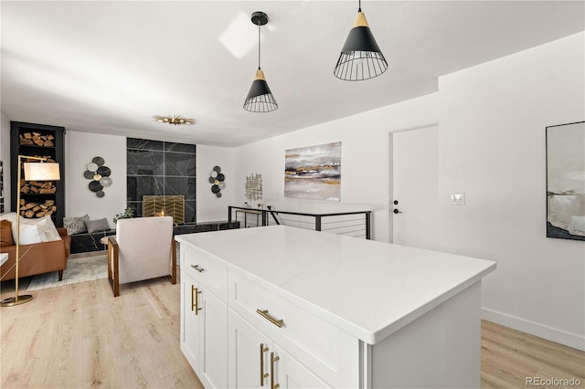 kitchen featuring decorative light fixtures, light hardwood / wood-style flooring, white cabinetry, and a center island