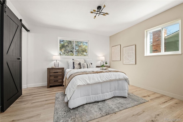 bedroom featuring a barn door and light wood-type flooring