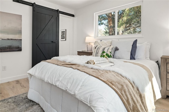 bedroom with a barn door and light hardwood / wood-style floors