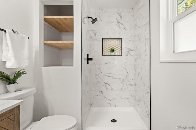 bathroom featuring toilet, vanity, and a tile shower