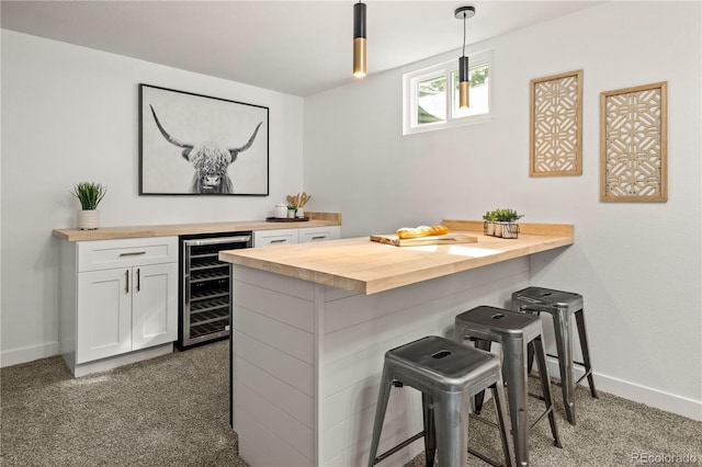 bar featuring pendant lighting, wooden counters, white cabinetry, wine cooler, and dark carpet