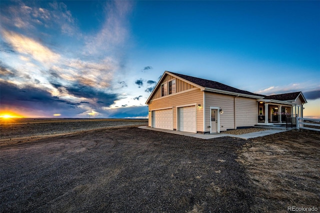 property exterior at dusk with a garage, driveway, and board and batten siding