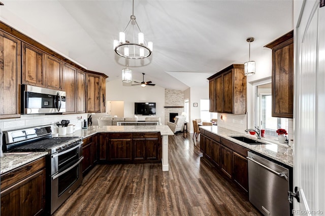 kitchen featuring dark wood finished floors, lofted ceiling, stainless steel appliances, a sink, and ceiling fan with notable chandelier