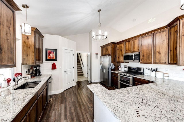 kitchen featuring stainless steel appliances, dark wood-style flooring, a sink, and light stone counters